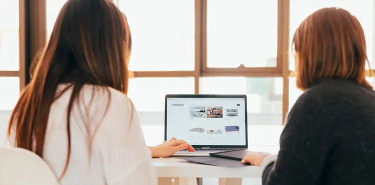 Two marketing specialists analyzing an e-commerce website product page on a laptop screen.
