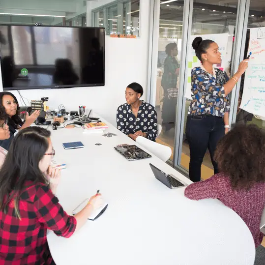 A marketing strategist leading a collaborative campaign planning session on a whiteboard in a modern conference room.
