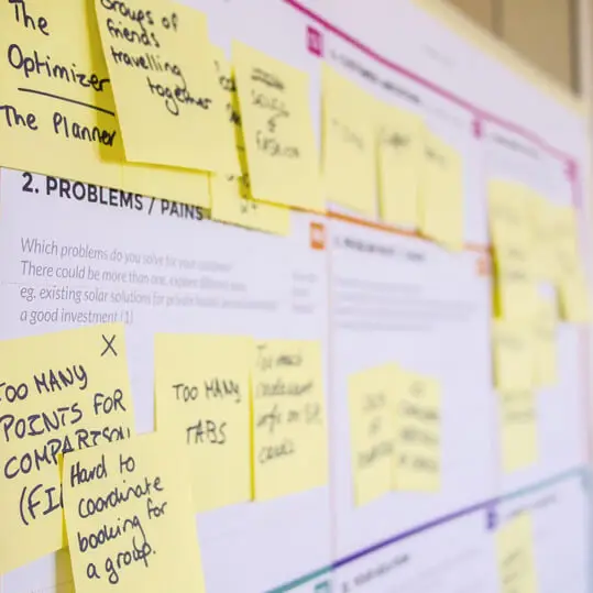 UX design brainstorming session with yellow sticky notes on a whiteboard under problems and pains section