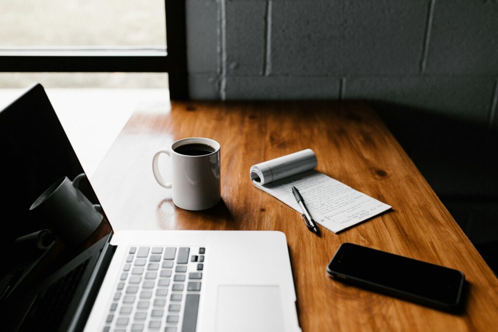Laptop on a desk with a coffee cup for someone writing a blog.